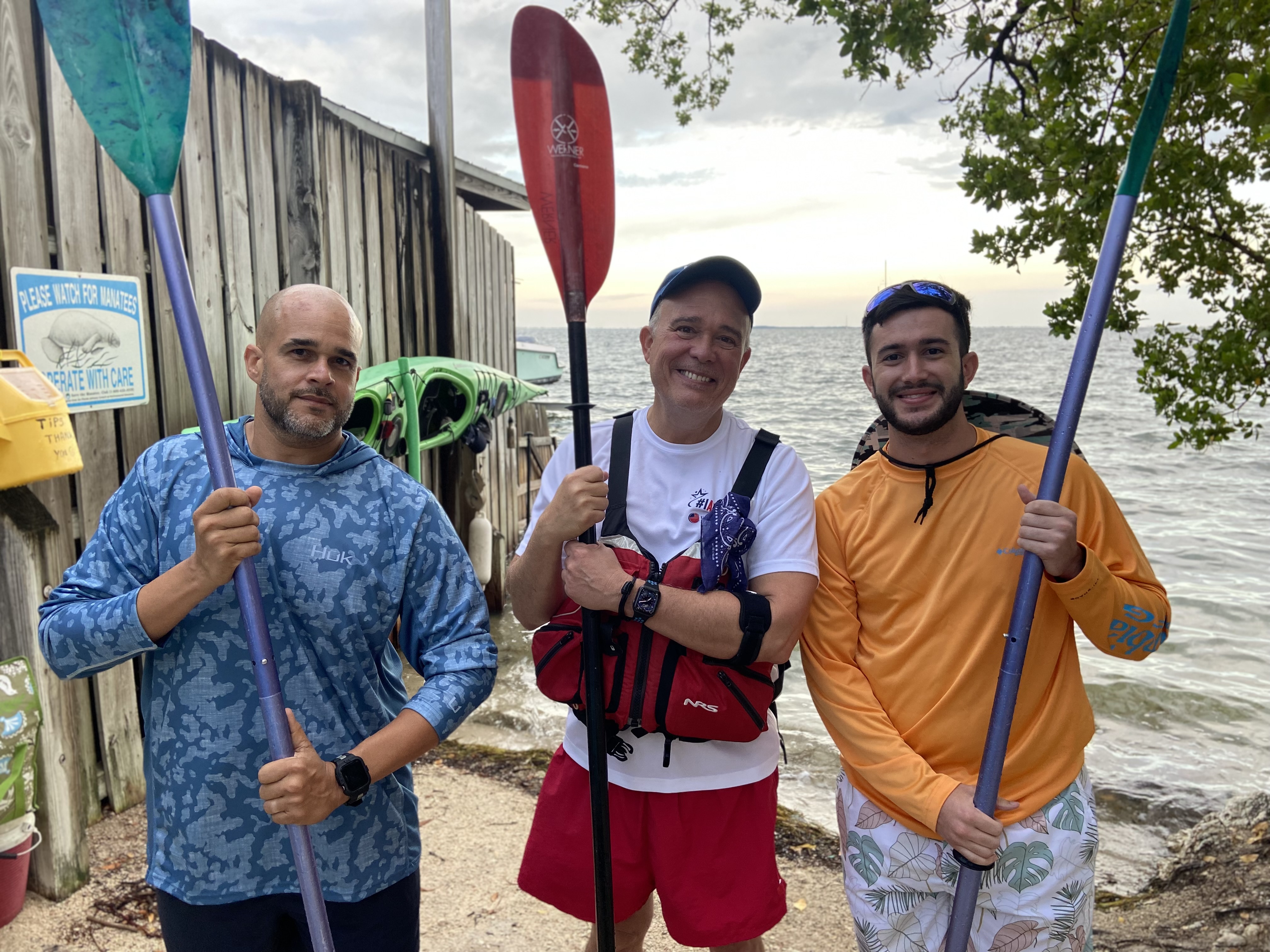 three men holding paddles for fundraising event